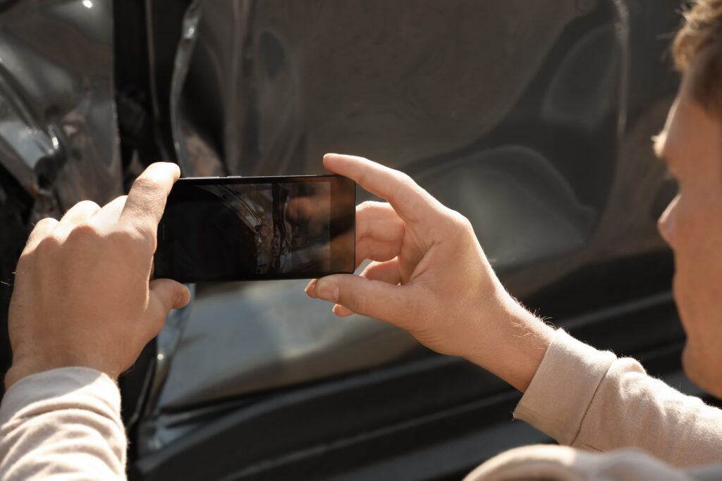 Driver photographing vehicle damage after a car accident